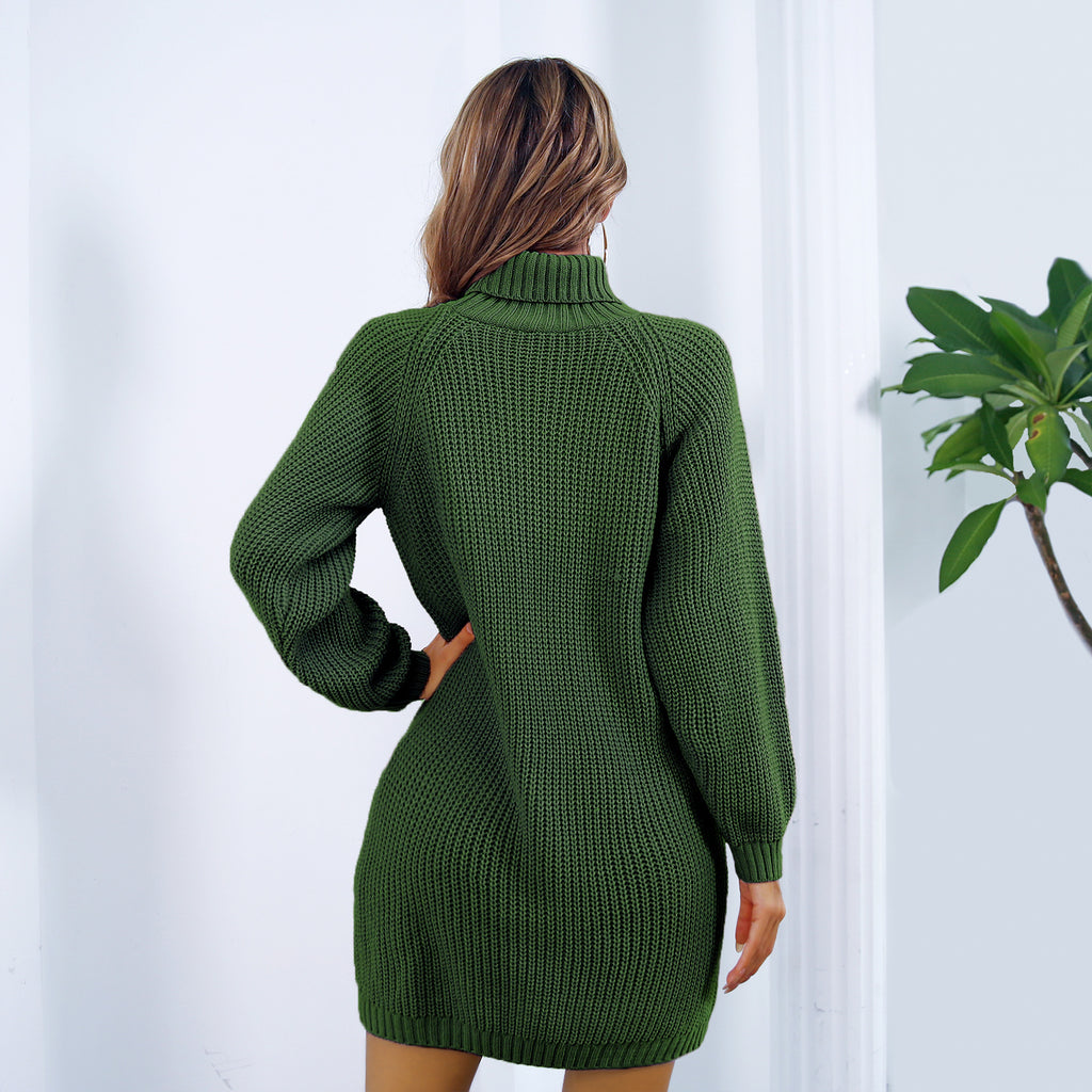 Green knitted dress worn by a person against a white wall with a plant on the right.