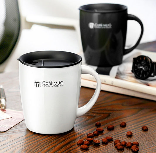 White mug with black lid on a wooden surface with scattered coffee beans, next to a black mug.