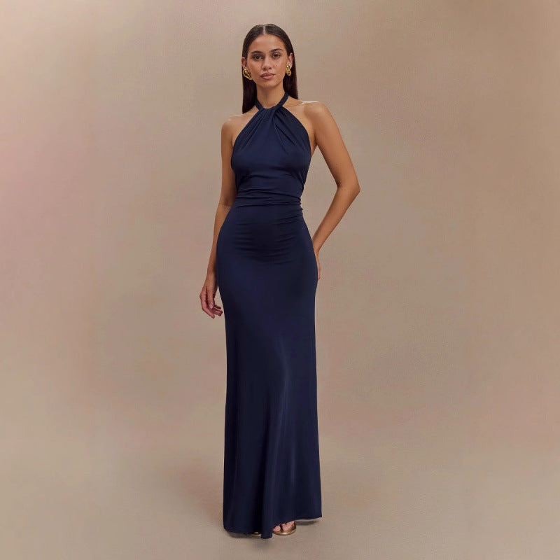 Woman wearing a navy blue halter neck gown against a beige background