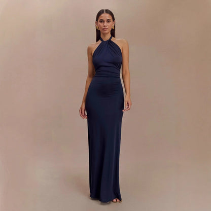 Woman wearing a navy blue halter neck gown against a beige background